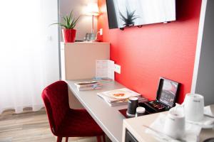 科尔马科尔马酒店 的一张带笔记本电脑和红色墙壁的书桌