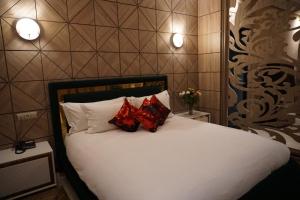 梅克内斯Hôtel Volubilis Meknès的卧室配有白色床和2个红色枕头