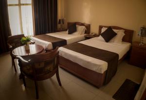 吉布提Comfort Hotel的酒店客房设有两张床和一张桌子。