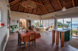 托弗海滩Pura Vida Tofo Beach Houses的一间带桌椅和海洋的客厅