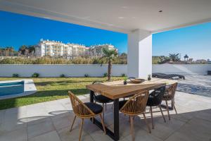 马尼尔瓦Villa moderne proche de la mer的美景庭院里的木桌和椅子