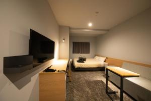 别府AMANEK Inn Beppu的配有一张床和一台平面电视的酒店客房