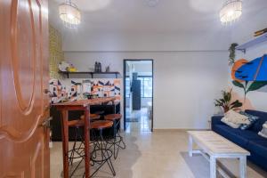 瓦加托La Casa - Stunning 1BHK Apartment - Vagator, Goa By StayMonkey的客厅配有桌子和蓝色沙发