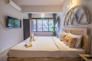 瓦加托La Casa - Stunning 1BHK Apartment - Vagator, Goa By StayMonkey的一间卧室设有一张大床和一个窗户。