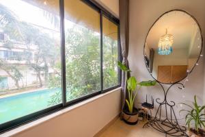 瓦加托La Casa - Stunning 1BHK Apartment - Vagator, Goa By StayMonkey的窗户房间里,镜子和植物