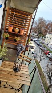 别洛瓦尔Apartman H8的阳台设有木凳和盆栽植物