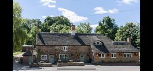 达文特里The Plough Inn Boddington的一座树木林立的老砖房