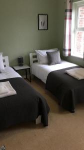 哈勒斯登Bullfinch House的一间卧室设有两张床和窗户。