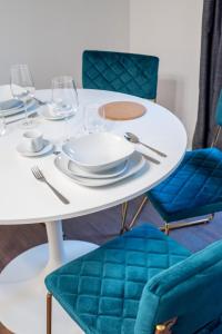 图尔昆Le Moja的一张带盘子的白色桌子、酒杯和蓝色椅子