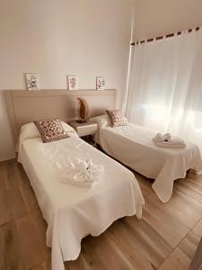 玛利亚镇La Pedrera Apart的客房内的两张床和白色床单