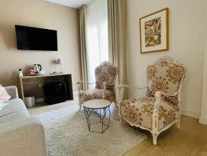 林孔-德拉维多利亚Añoreta Suites的客厅配有两把椅子和电视