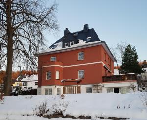 奥厄Pension Irmisch的一座大红房子,屋顶上积雪