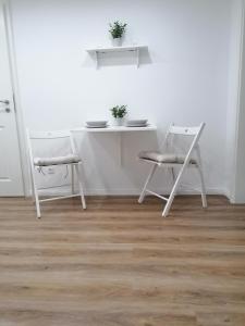 新明斯特Nordunterkunft的白色的房间里摆放着白色的桌子和椅子