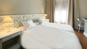 奥卡尼亚Hotel Plaza Mayor的卧室配有一张白色大床和一张书桌