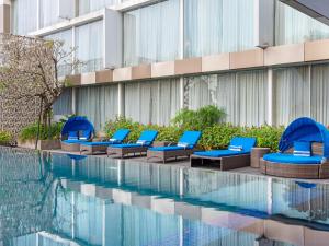 日惹ARTOTEL Suites Bianti Yogyakarta, CHSE Certified的游泳池旁的一排蓝色躺椅