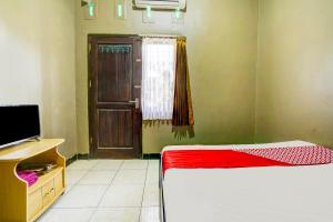 ManiskalerSuper OYO 1I3676 Wisma Al-fahmi Syariah的一间设有床、电视和门的房间
