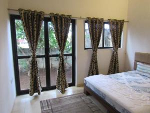 卡尔贾特Retreat Holiday Homes, Twin Chalets at Sparsh Resorts and Chalets, Karjat的一间卧室设有一张床和两个大窗户
