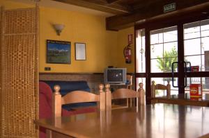 QuéntarQuéntar Hotel Rural的客厅配有桌椅和电视。