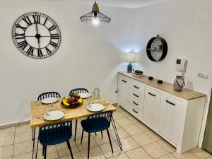圣丹尼斯Nouveauté - L'Oasis - T3 - 70 M2 - Jacuzzi的厨房配有桌椅和墙上的时钟