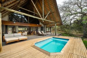 Manyoni Private Game ReserveRhino River Lodge的木甲板上设有游泳池的房子