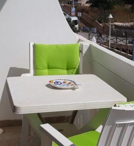 塞勒玛Salema Beach Apartment的阳台配有一张白色桌子和一张绿色椅子。