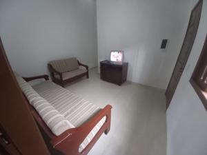 伯迪亚哥Casa de praia Indaiá Bertioga的一间带床、椅子和电视的房间