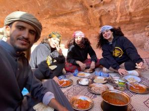 瓦迪拉姆Wadi Rum Cave Camp &Jeep Tour的一群坐在桌子旁吃食物的人