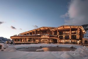 塞尔瓦迪加尔代纳山谷Granbaita Dolomites的一座大建筑,在雪中设有一个池塘