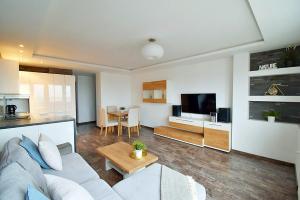 格丁尼亚Avis Apartments - Gdynia Władyslawa 32的一间带白色沙发的客厅和一间厨房
