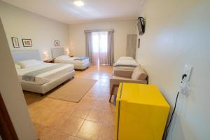 博尼图Pousada Girassol的酒店客房带两张床和一张黄色桌子