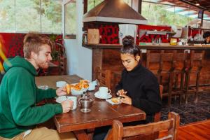马丘比丘Nativus Hostel Machu Picchu的坐在餐桌旁吃食物的男人和女人