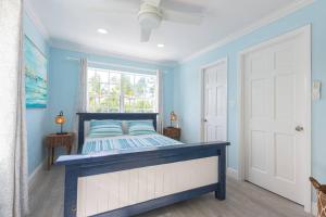 拿骚Harbour Mews - Oceanfront Townhouse的蓝色的卧室设有床和窗户