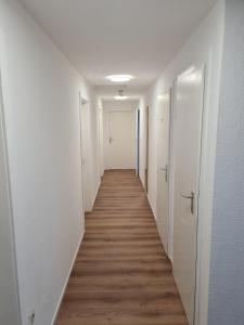 斯图加特拉姆酒店的长长的走廊设有白色的墙壁和木地板