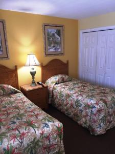 彭萨科拉海滩Soundside Holiday Beach Resort的酒店客房设有两张床和一张桌子上的台灯。