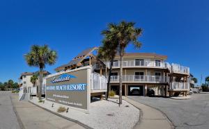 彭萨科拉海滩Soundside Holiday Beach Resort的一座棕榈树建筑,前面有一个标志