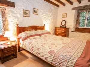 兰鲁斯特Nant Cottage的一间卧室配有一张床、一张桌子和闹钟