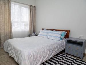 内罗毕Nyumba Nzuri 2 bedroom apartment central of NBO的一间卧室配有一张床、床头柜和窗户