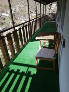 KosovoGUEST HOUSE ELENA的阳台配有两张桌子和一张长凳