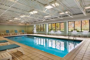 布里奇波特Wingate by Wyndham Bridgeport Clarksburg的游泳池位于酒店客房内,设有桌椅和窗户。