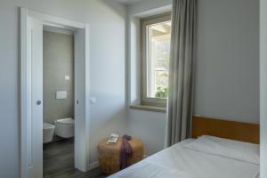 托斯科拉诺-马德尔诺Relais Zenner的一间卧室设有一张床、一个窗口和一个卫生间