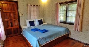库德岛TA YAI HOMESTAY (ตา ยาย โฮมสเตย์)的一间卧室配有一张带蓝色床单的床和一扇窗户。