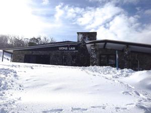 Smiggin HolesThe Lions Lair Lodge的前面有雪的建筑