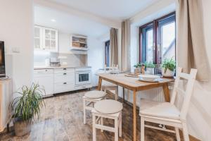 捷克克鲁姆洛夫Konekt Apartment的白色的厨房配有木桌和椅子