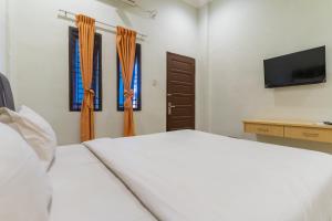 棉兰Vandolia Guest House Mitra RedDoorz的卧室配有白色的床和2扇窗户。