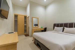 棉兰Vandolia Guest House Mitra RedDoorz的一间卧室配有一张大床和电视