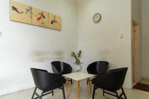 棉兰Vandolia Guest House Mitra RedDoorz的一间设有四把椅子、一张桌子和闹钟的房间