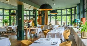 霍尔滕胡格霍尔顿餐厅酒店的餐厅设有白色的桌椅和窗户。