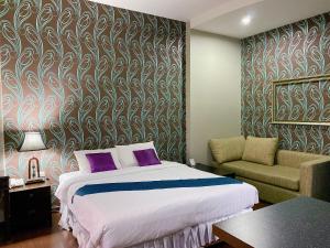 Si Maha PhotThe Desiign Hotel - SHA的一间卧室配有一张床、一张沙发和一把椅子
