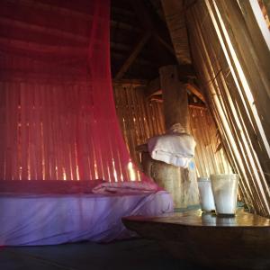 小玉米岛ENSUEÑOS NATURAL RESERVE Little Corn Island Nicaragua的红色窗帘的房间的一张床位