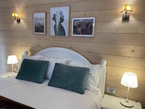 布朗喀尔巴阡木屋酒店的一间卧室配有一张带两盏灯的床,墙上挂有图片